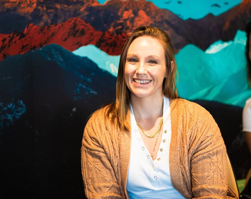 An agent smiling in front of the mountain mural