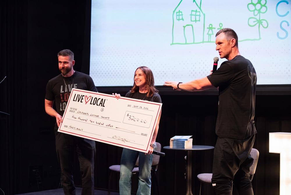 Presenting a Live Love Local donation cheque on stage at Thrive Not Survive X